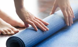 Close up of woman rolling up yoga mat